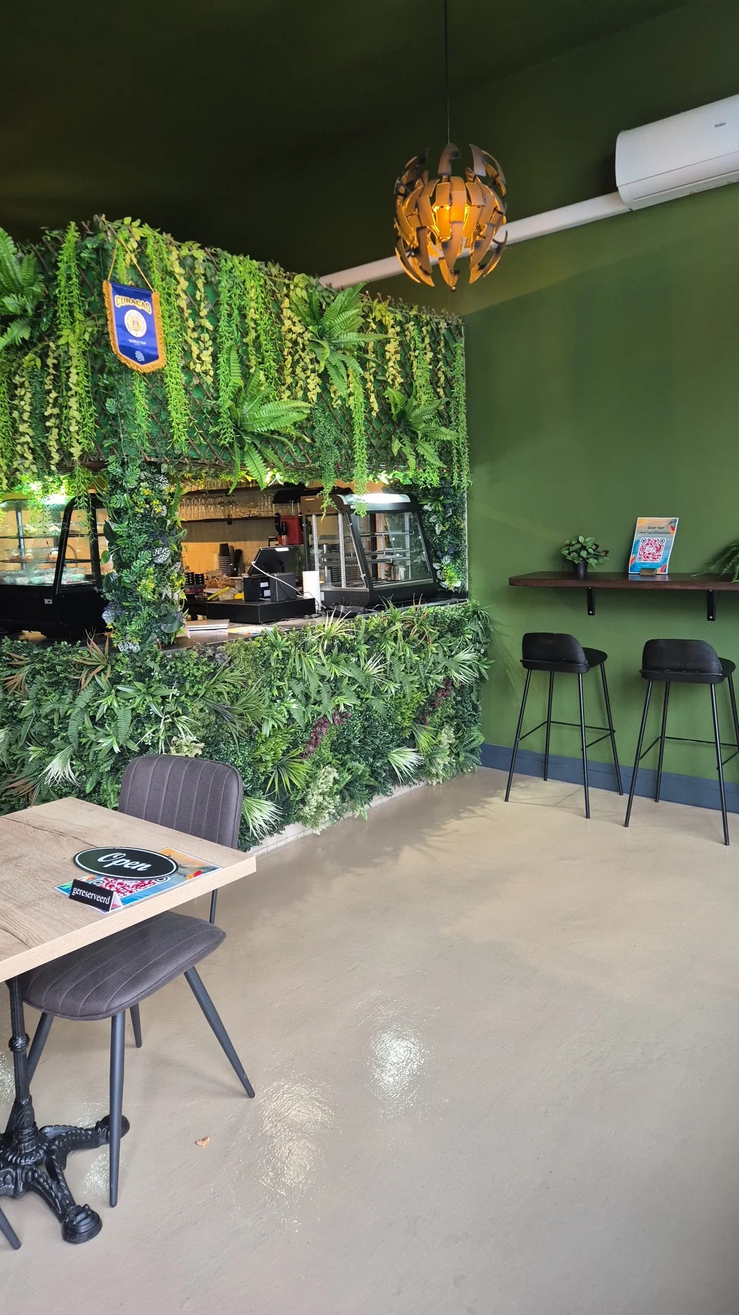 De toonbank met vitrine, omlijst door een wand van planten