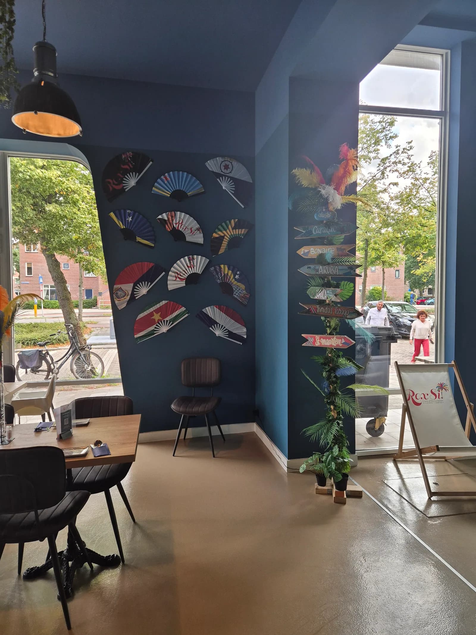 Wand met waaiers in de kleuren van de Caribische eilanden en houten wegwijzers