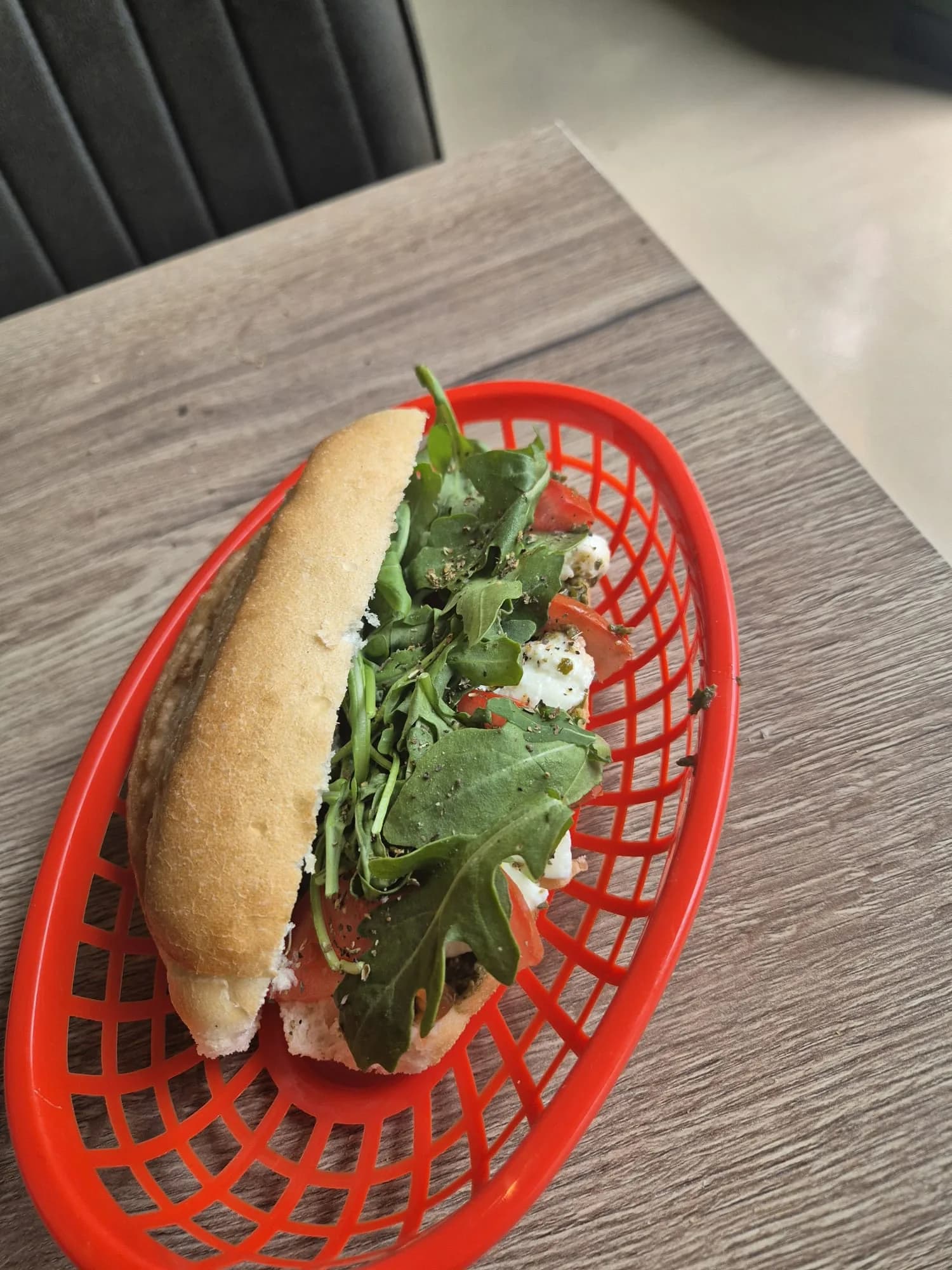 Belegd broodje met rucola, tomaat en verse kaas in een rood mandje